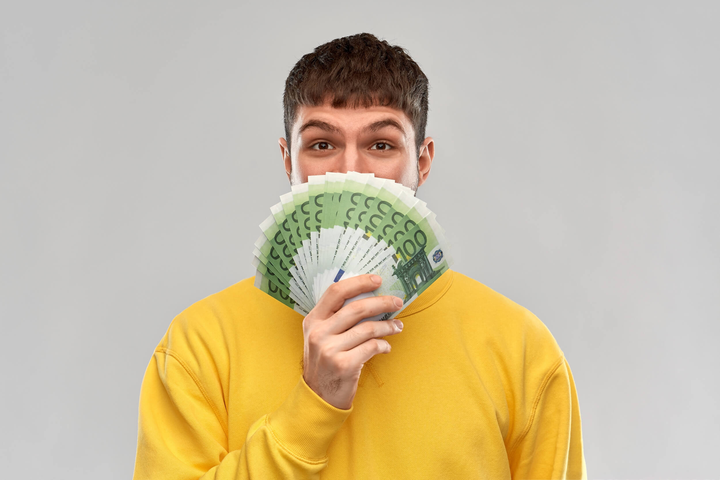 homme tenant une série de billets de 100 Euros dans les mains