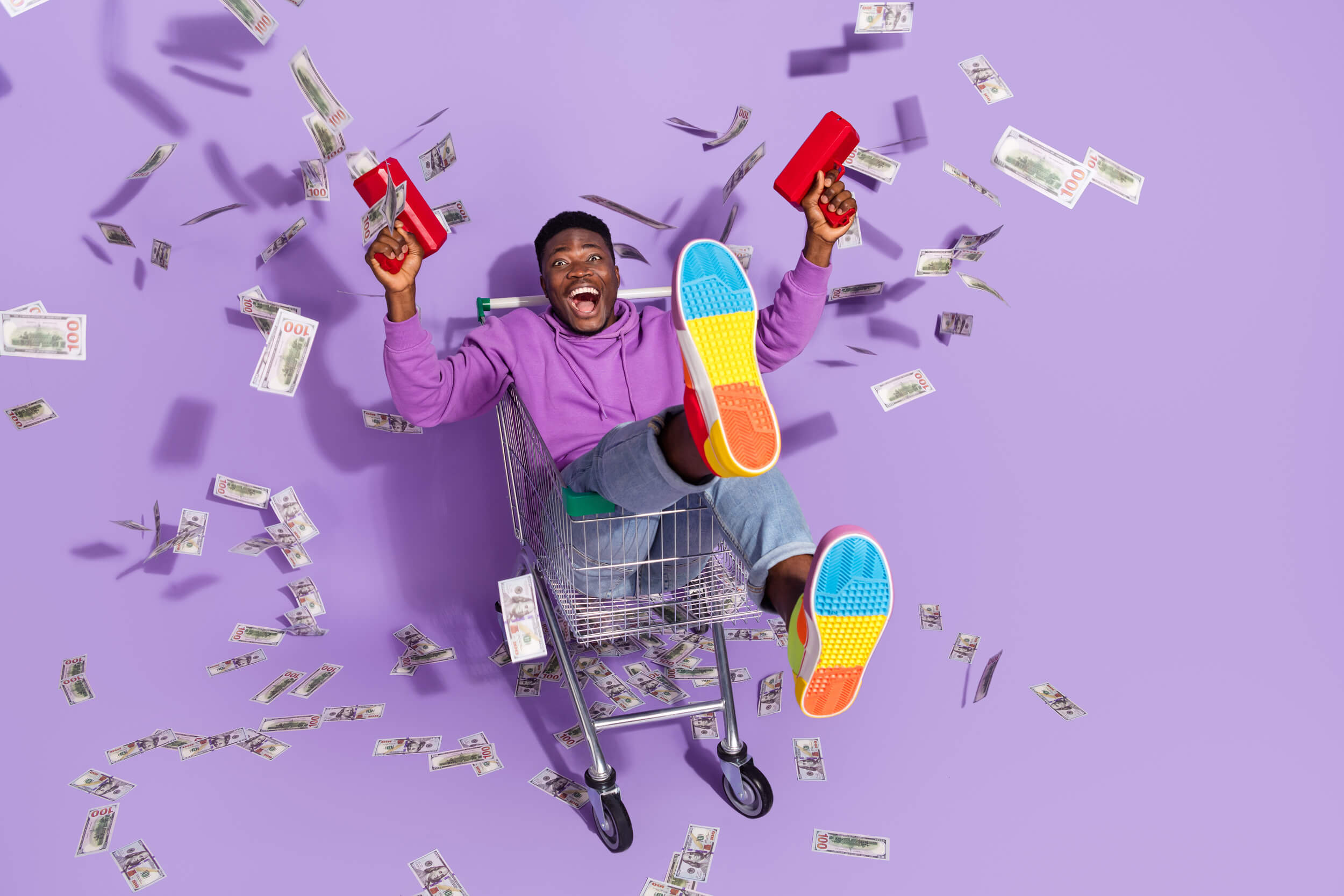 homme dans un caddie avec de l'argent qui lui tombe dessus