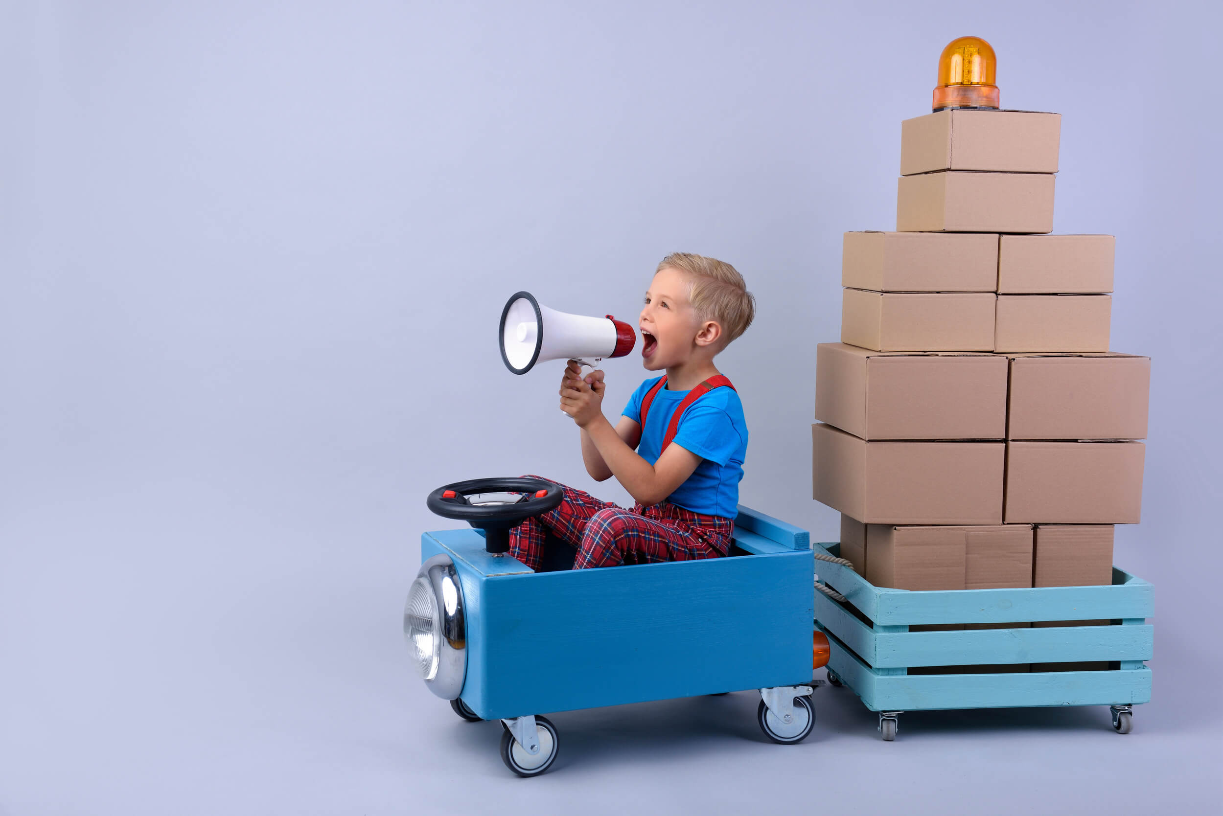 enfant dans un petite camion transportant des cartons dans une remorque