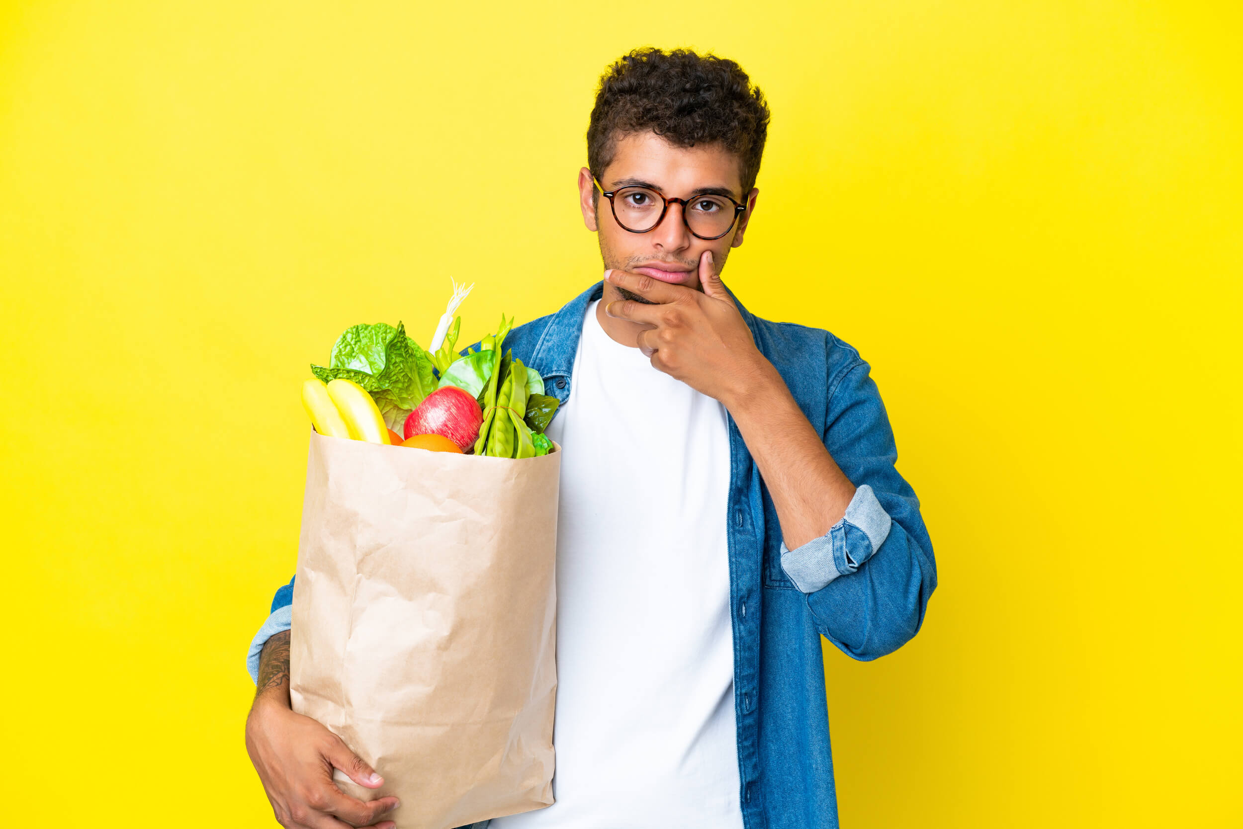 Un mec avec un sac de course rempli de fruits et légumes