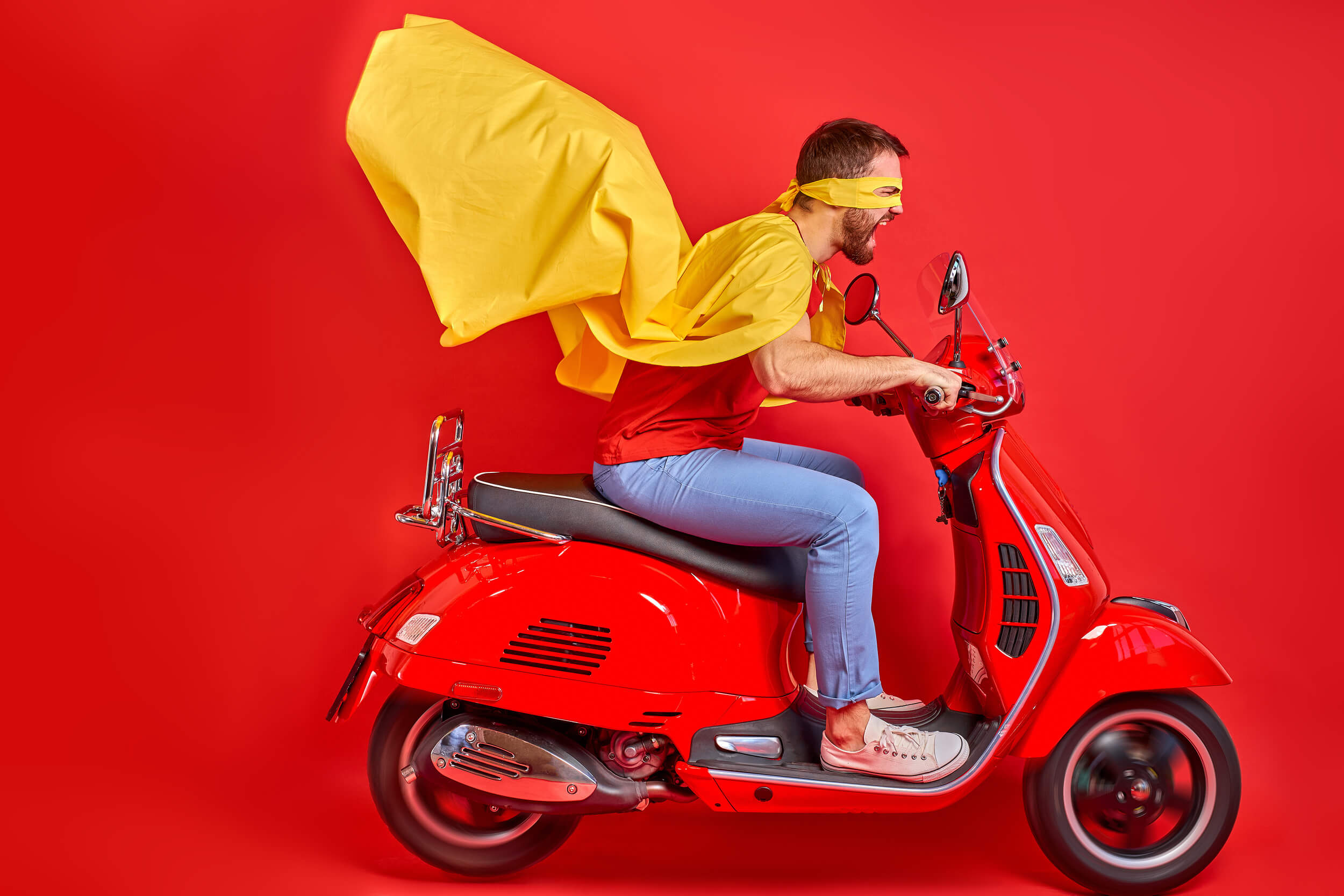 homme en scooter avec une cape de super héros